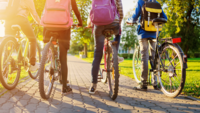 Vier Kinder mit Rucksack stehen mit Fahrrädern auf der Straße