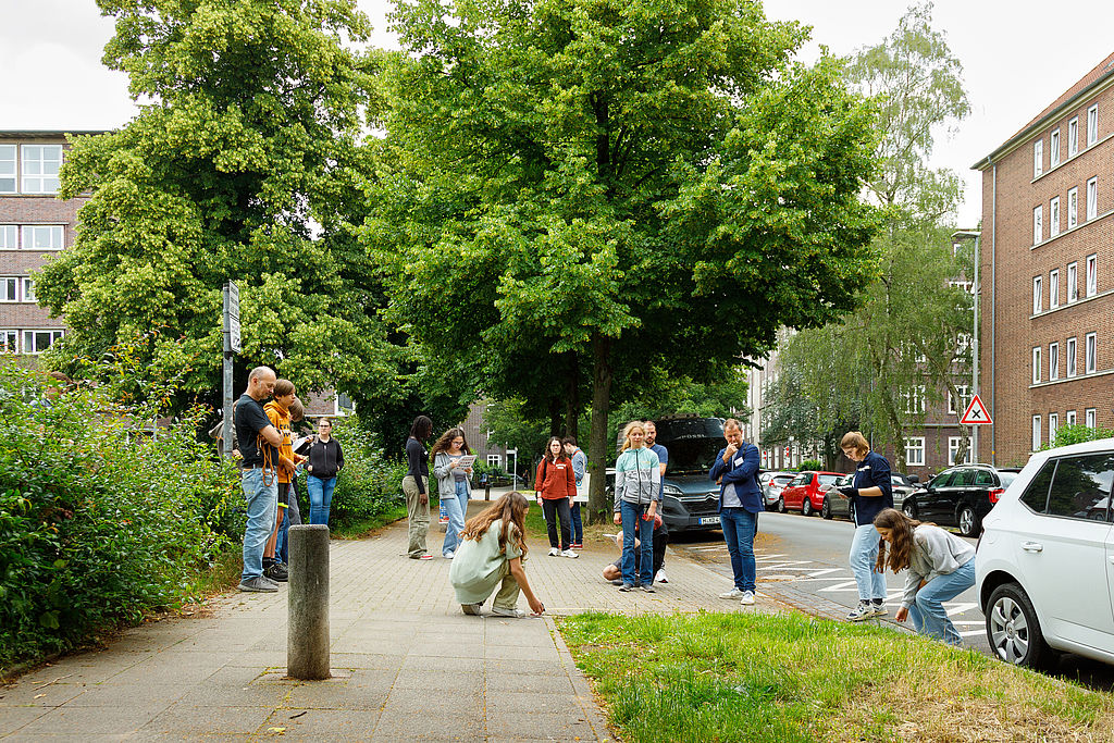 Mehrere Kinder und Jugendliche messen die Breite eines Gehwegs