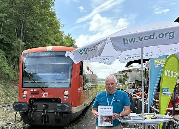 Foto: VCD-Infostand beim Maultaschenfest direkt an der Bahnstrecke – im Hintergrund fährt ein Zug vorbei.