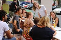 Eine Gruppe junger Menschen sitzt um einen langen Tisch und diskutiert