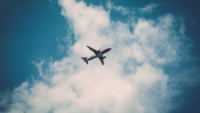 Ein Flugzeug am Himmel mit Wolke im Hintergrund