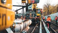 Bauarbeiter arbeiten mit schweren Fahrzeugen an einem Gleisbett