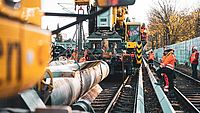 Bauarbeiter arbeiten mit schweren Fahrzeugen an einem Gleisbett