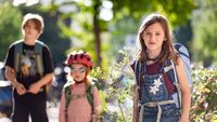 Drei Kinder in unterschiedlichem Alter auf dem Schulweg