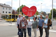 sechs Menschen stehen vor einem Busbahnhof und halten ein großes rotes Herz hoch auf dem steht: "Ein Herz für den ZOB"