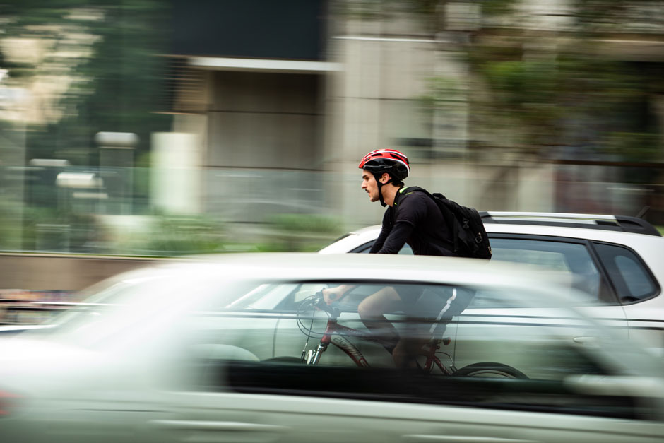 Ein Mann auf dem Fahrrad fährt zwischen Autos auf der Straße
